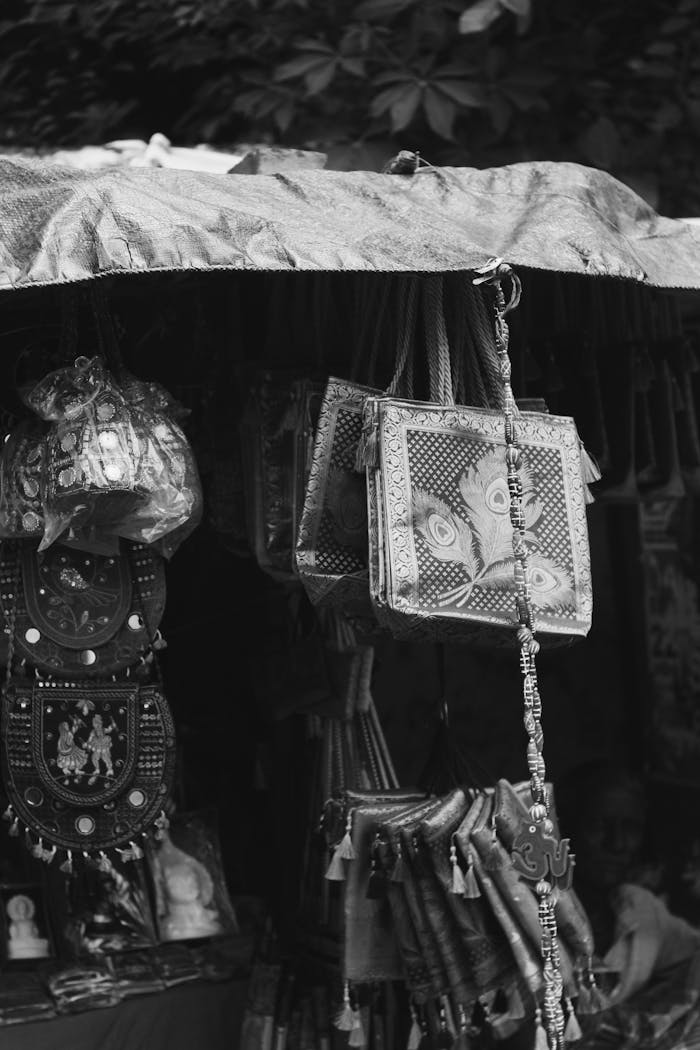 Black and white photo showcasing a variety of handcrafted bags and items in an outdoor market setting.